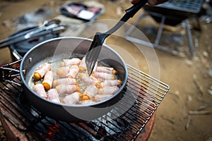 Breakfast for all ages,Pigs in Blankets or Mini sausages wrapped in smoked bacon on a hot frying pan on a charcoal grill at