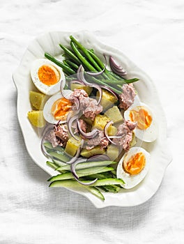 Breakfast, appetizers salads - boiled eggs, potatoes, string beans, red onion, cucumber, canned tuna salad on a light background,