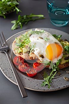 Breakfast avocado sandwich with fried egg and tomato