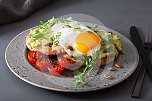 Breakfast avocado sandwich with fried egg and tomato