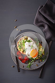 Breakfast avocado sandwich with fried egg and tomato