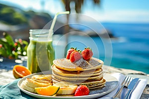 Breakfast on the background of the sea. Kiwi smoothies and sweet pancakes decorated with strawberries and honey