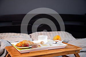 Breakfast in bed with coffee, croissants, strawberries and honey