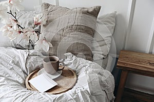 Breakfast in bed concept. Cup of coffee on wooden tray. Blank greeting card, invitation mockup. Bedroom view. Blurred