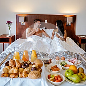 Breakfast in bed, couple drinking coffee in bed in the morning at an luxury hotel room