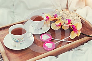 Breakfast in bed in Valentines day. Cup of tea and sweet candies. Love or holiday concept