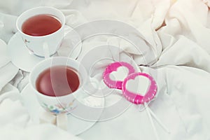 Breakfast in bed in Valentines day. Cup of tea and sweet candies. Love or holiday concept