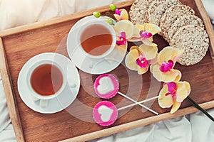 Breakfast in bed in Valentines day. Cup of tea and sweet candies. Love or holiday concept