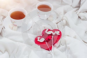 Breakfast in bed in Valentines day. Cup of tea and sweet candies. Love or holiday concept