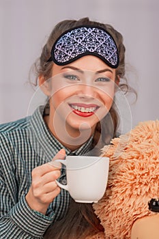 Breakfast in bed. Young woman smiles, drinks coffee tea, close-up portrait