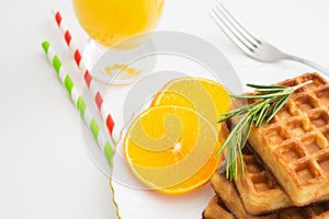 Breakfast with belgium waffles with rosemary and orange slices. Closeup view