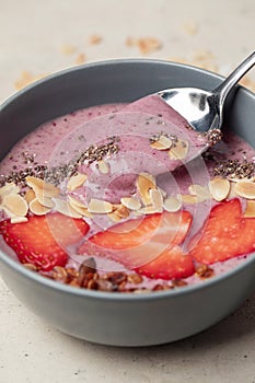 Breakfast berry smoothie bowl with chia seeds, oatmeal, almonds and strawberries.