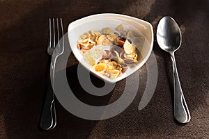 Breakfast bowl of cornflake and milk with spoon and fork in the morning.