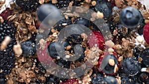 Breakfast bowl granola muesli top view. Ingredients falling in oatmeal yoghurt