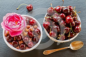 Breakfast bowl with yogurt, granola or muesli or oat flakes, fresh cherries and nuts. Black stone background, top view