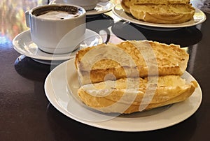 Breakfast at Brazil with french bread toasted with butter on the plate with capuccino on table