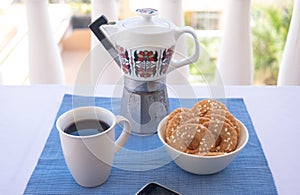 Breakfast or break outdoor on the balcony with coffe cup and homemade biscuits. Mobile phone in the corner. Vintage ceramic coffee