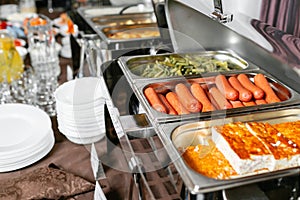 Breakfast buffet in hotel. Lots of heated trays ready for service. Metal containers with warm meals