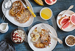 Breakfast - caramel french toast with banana, cottage cheese with granola and pomegranate, fresh grapefruit on a blue background.