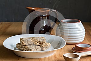 Breakfast cereal bars in bowl, with milk and honey jar in background