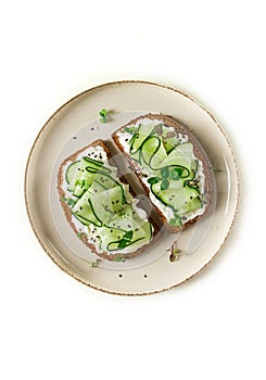 Breakfast, cereal bread sandwiches, cream cheese, sliced cucumber, with micro greenery on a light table, close-up, top