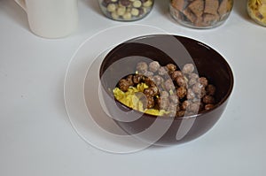 Breakfast cereal, chocolate balls in a brown bowl. Healthy breakfast. Diet Bowl and spoon with corn flakes isolated on