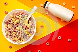 Breakfast cereal concept, Fruit ring cereals in bowl and milk in bottle on colorful background