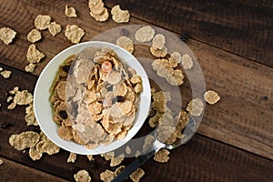 Breakfast cereal cornflakes in a bowl on a wooden table background