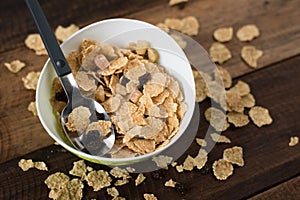Breakfast cereal cornflakes in a bowl on a wooden table background
