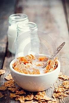 Breakfast cereal wheat flakes in ceramic bowl and milk bottles o