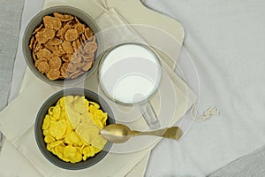 Breakfast cereals, cornflakes in bowls and cup of milk on a light background. Fast food. Top view.