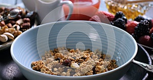 Breakfast cereals falling on a bowl with berries and dry fruits