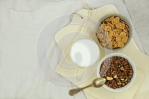 Breakfast cereals, flakes in bowls and cup of milk on a light background. Fast food. Top view.