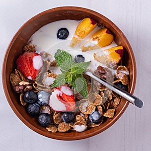 Breakfast of cereals and fruits with yoghurt in Clay bowls on a white tablecloth  top view