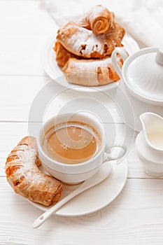 Breakfast with coffee and bagels with orange jam on a white wooden table