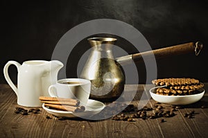 breakfast with coffee and cookies/coffee cup with cinnamon, old pot, creamer and chocolate cookies on a wooden table. selective