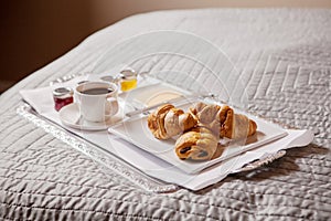 Breakfast coffee and croissants pain au chocolat on bed