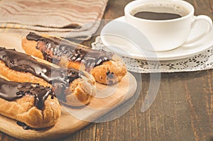 Breakfast with coffee cup and eclairs/breakfast with coffee cup and eclairs on a wooden table. Selective focus abd copy space