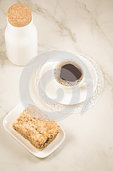 Breakfast with coffee and a dessert/bottle, coffee cup and dessert on a white marble table. Top view