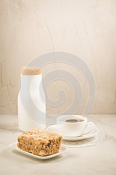 breakfast with coffee and a dessert/bottle, coffee cup and dessert on a white table. Selective focus