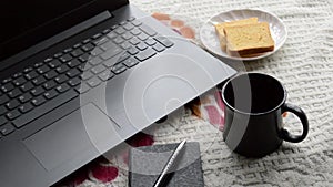 Breakfast coffee in morning sunlight with laptop computer black color pen and personal organizer notebook, ceramic cup saucer and