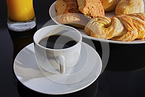 Breakfast. Coffee white cup, plate with bread on dark table