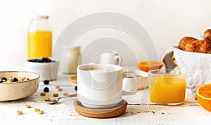 Breakfast concept with cup of coffee, croissants, wholegrain hoops, milk, orange juice, yogurt and blueberries