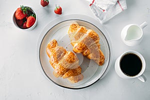 Breakfast concept. Cup of coffee, freshly baked croissants and fresh strawberry. Top view