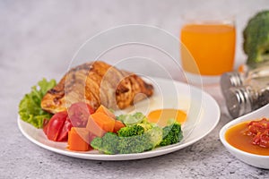 Breakfast consisting of bread, fried eggs, broccoli, carrots, tomatoes and lettuce on a white plate