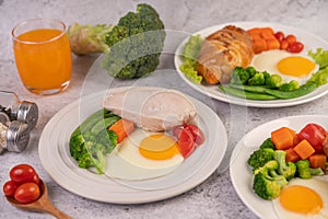 Breakfast consisting of bread, fried eggs, broccoli, carrots, tomatoes and lettuce on a white plate