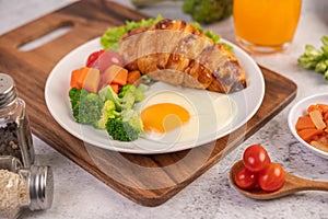 Breakfast consisting of bread, fried eggs, broccoli, carrots, tomatoes and lettuce on a white plate