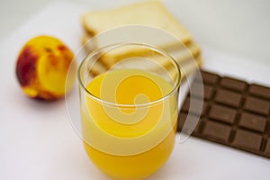 Breakfast consisting of natural orange juice, ripe peach, white bread and milk chocolate photo