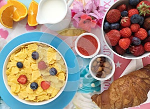 Breakfast with cornflakes, milk, croissants, jam, fresh fruits and almonds.