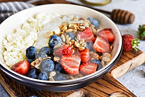 Breakfast - cottage cheese with berries and a cup of coffee, top view. Granola with nuts, honey and strawberries